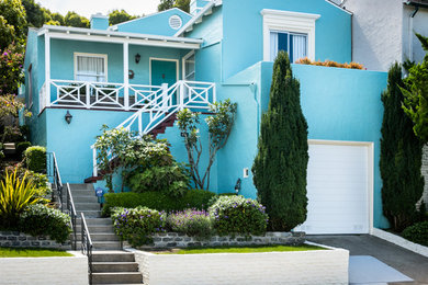 Diseño de fachada azul clásica de tamaño medio a niveles con revestimiento de estuco y tejado a dos aguas