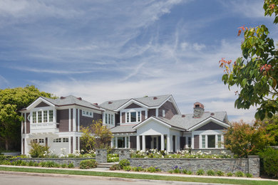Immagine della villa grande marrone classica a due piani con rivestimento in legno, tetto a padiglione e copertura a scandole