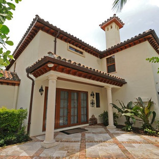 Imagen de fachada de casa beige, mediterránea, grande, de dos plantas, con revestimiento de estuco, tejado a cuatro aguas y tejado de teja de barro