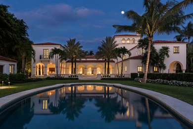 Example of a huge tuscan beige three-story stucco house exterior design in Miami with a hip roof and a tile roof