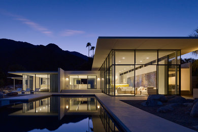 Cette image montre une façade de maison blanche minimaliste en stuc de plain-pied avec un toit plat.