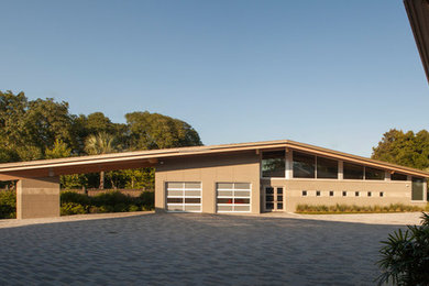 Diseño de fachada de casa beige grande de dos plantas con revestimiento de hormigón, tejado a cuatro aguas y tejado de metal
