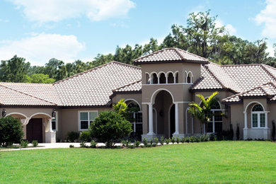 На фото: большой, одноэтажный, бежевый дом в средиземноморском стиле с облицовкой из цементной штукатурки и вальмовой крышей