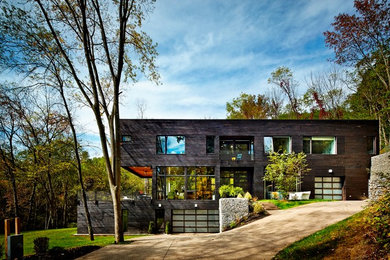 Modelo de fachada de casa negra moderna grande de tres plantas con revestimiento de madera, tejado plano y techo verde