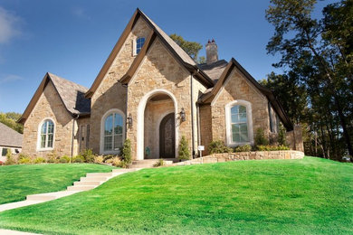 Cette photo montre une grande façade de maison beige méditerranéenne en pierre de plain-pied avec un toit à deux pans et un toit en shingle.