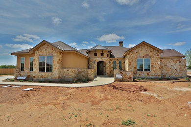 Inspiration for a mid-sized mediterranean beige one-story stone gable roof remodel in Dallas