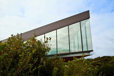 Diseño de fachada marrón marinera grande de dos plantas con revestimiento de metal, tejado plano y tejado de metal