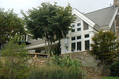 Imagen de fachada blanca tradicional grande de dos plantas con revestimiento de madera y tejado a dos aguas