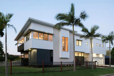 Diseño de fachada de casa blanca costera de tamaño medio de dos plantas con revestimientos combinados, tejado plano y tejado de metal