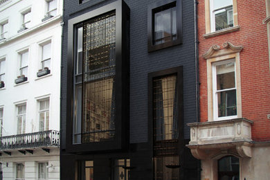 Photo of a black contemporary brick house exterior in London with a flat roof.