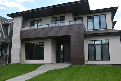 This is an example of a large and white contemporary two floor render detached house in Calgary with a shingle roof.