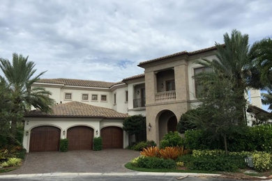 Mid-sized elegant beige two-story stucco house exterior photo in Miami with a hip roof and a tile roof