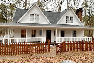 Modelo de fachada de casa blanca tradicional de tamaño medio de dos plantas con revestimiento de madera, tejado a dos aguas y tejado de teja de madera
