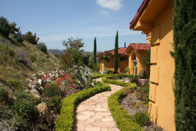 Large tuscan yellow two-story stone house exterior photo in San Diego with a hip roof and a tile roof