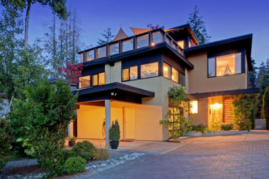 Cette image montre une grande façade de maison beige minimaliste en stuc à deux étages et plus avec un toit plat.
