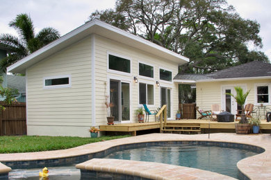 Example of a small trendy yellow one-story concrete fiberboard house exterior design in Tampa with a shed roof and a shingle roof