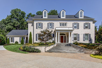 Cette image montre une grande façade de maison beige traditionnelle en brique à un étage avec un toit à deux pans et un toit en shingle.