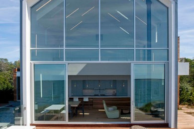 Ejemplo de fachada actual de dos plantas con revestimiento de vidrio y tejado a dos aguas