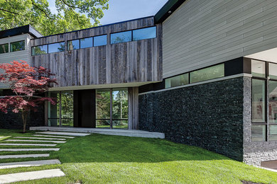 Modelo de fachada de casa gris moderna grande de dos plantas con revestimientos combinados y tejado plano