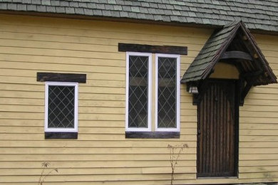 Foto de fachada amarilla de estilo americano pequeña de una planta con revestimiento de madera y tejado a dos aguas