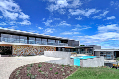 Mittelgroßes Modernes Einfamilienhaus mit Steinfassade, Flachdach und Blechdach in Melbourne