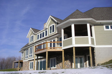 Cette photo montre une très grande façade de maison grise chic à un étage avec un revêtement en vinyle, un toit à quatre pans et un toit en shingle.