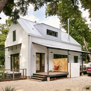 Photo of a small and white country two floor house exterior in Austin with metal cladding and a pitched roof.