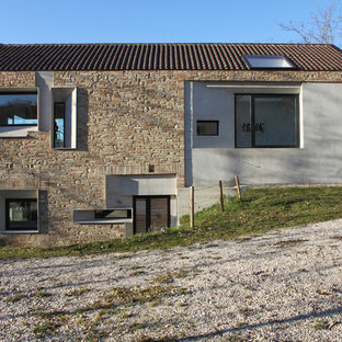 Esempio della facciata di una casa country a due piani con rivestimenti misti e tetto a capanna