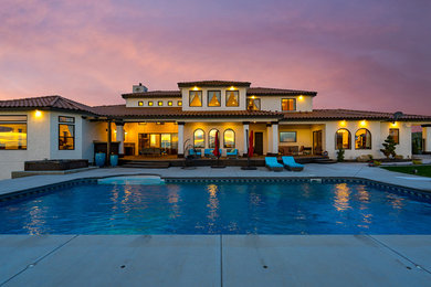 Example of a tuscan white two-story stucco house exterior design in Seattle with a hip roof and a tile roof