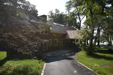 Immagine della villa ampia verde rustica a tre piani con rivestimento in legno, tetto a capanna e copertura mista