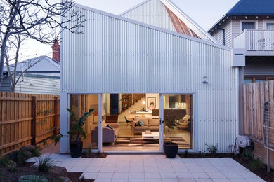 Cette image montre une façade de maison métallique urbaine à un étage avec un toit en appentis et un toit en métal.