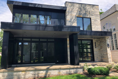Modelo de fachada de casa negra minimalista grande de dos plantas con revestimiento de ladrillo y tejado plano