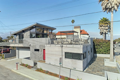 Aménagement d'une grande façade de maison grise contemporaine en béton à un étage avec un toit en appentis.