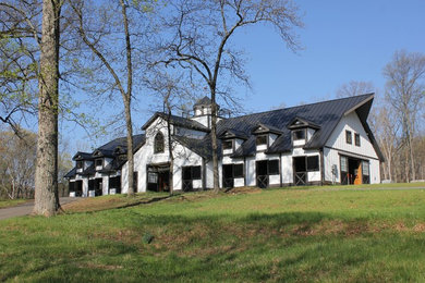 Modelo de fachada blanca de estilo de casa de campo extra grande de dos plantas con revestimiento de madera y tejado a dos aguas