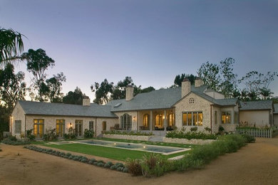 Cette photo montre une grande façade de maison grise chic en pierre de plain-pied avec un toit à deux pans et un toit en shingle.