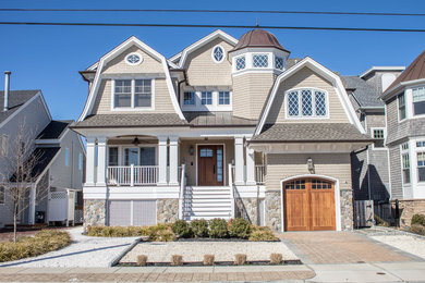 Foto de fachada de casa beige costera grande de tres plantas con revestimiento de madera, tejado a doble faldón y tejado de teja de madera