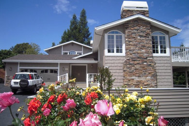 Modelo de fachada de casa beige clásica grande a niveles con revestimiento de madera, tejado a dos aguas y tejado de teja de madera