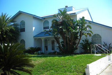 Example of a large beach style white two-story concrete gable roof design in Jacksonville