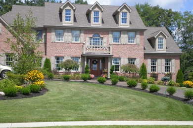 Inspiration for a large timeless red two-story brick exterior home remodel in Cleveland with a shingle roof