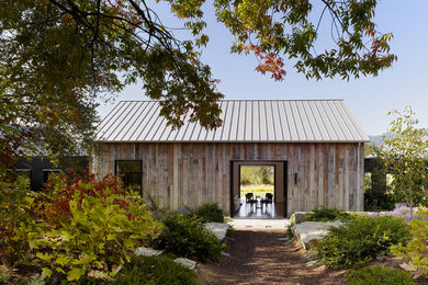 Diseño de fachada de estilo de casa de campo de una planta con revestimiento de madera y tejado a dos aguas