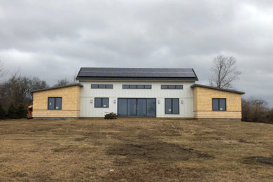 Réalisation d'une façade de maison design avec un toit à deux pans et un toit en shingle.