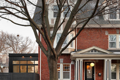 Idée de décoration pour une façade de maison rouge tradition en brique à un étage avec un toit à deux pans et un toit en shingle.