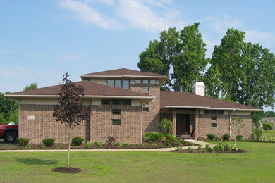 Пример оригинального дизайна: большой, двухэтажный, кирпичный, коричневый дом в современном стиле с вальмовой крышей
