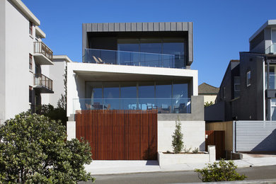 Exemple d'une façade de maison grise tendance à un étage avec un toit plat et un revêtement mixte.