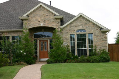 Cette image montre une façade de maison beige traditionnelle en brique de taille moyenne avec un toit à deux pans et un toit en shingle.