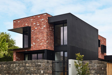 Diseño de fachada de casa negra moderna de tamaño medio de dos plantas con revestimiento de aglomerado de cemento, tejado plano y tejado de metal