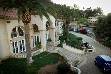 Diseño de fachada de casa beige mediterránea grande de dos plantas con revestimiento de estuco, tejado a cuatro aguas y tejado de teja de barro