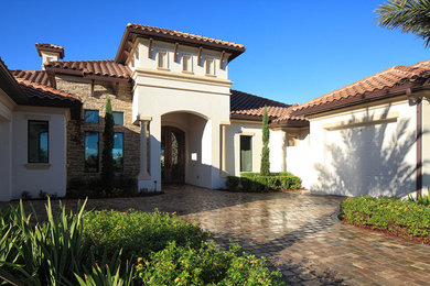 Huge mediterranean white one-story stucco house exterior idea in Orlando with a tile roof