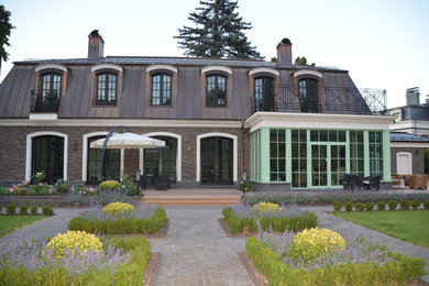 Ejemplo de fachada de casa marrón tradicional de tamaño medio de dos plantas con revestimiento de ladrillo, tejado a la holandesa y tejado de metal
