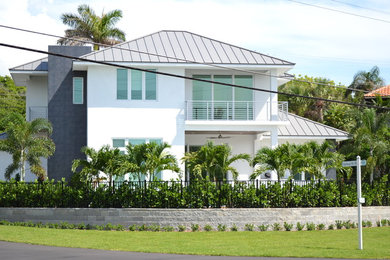 This is an example of a large and white modern two floor clay detached house in Miami with a mansard roof and a metal roof.